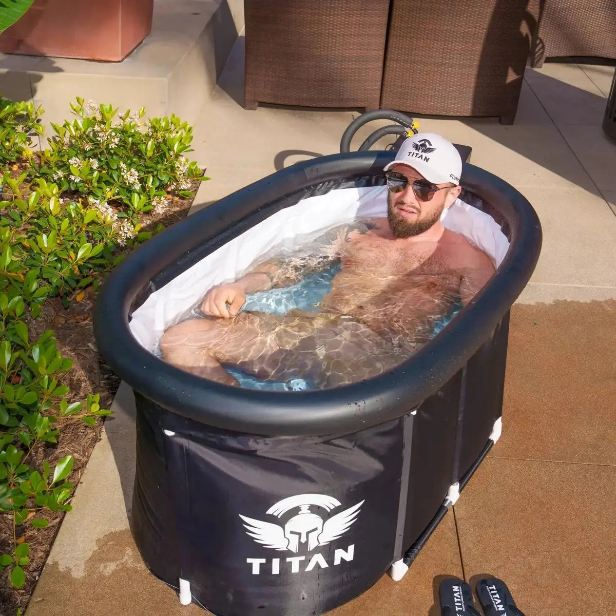 Man relaxing in a portable hot tub branded 'Titan' outdoors.