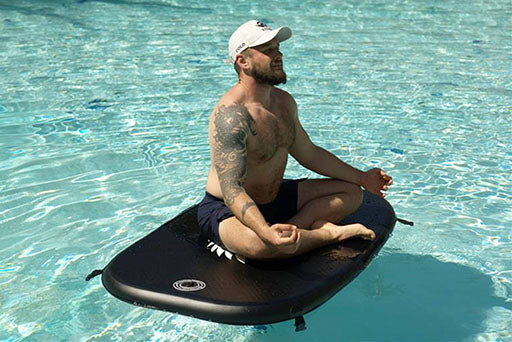 Man meditating cross legged on Titan Triumph cold plunge cover floating in a pool, demonstrating durability and weight support