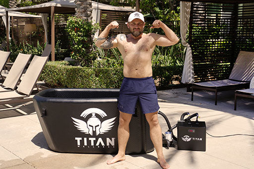 Man flexing beside Titan Triumph cold plunge and chiller on poolside patio, portable oval ice bath