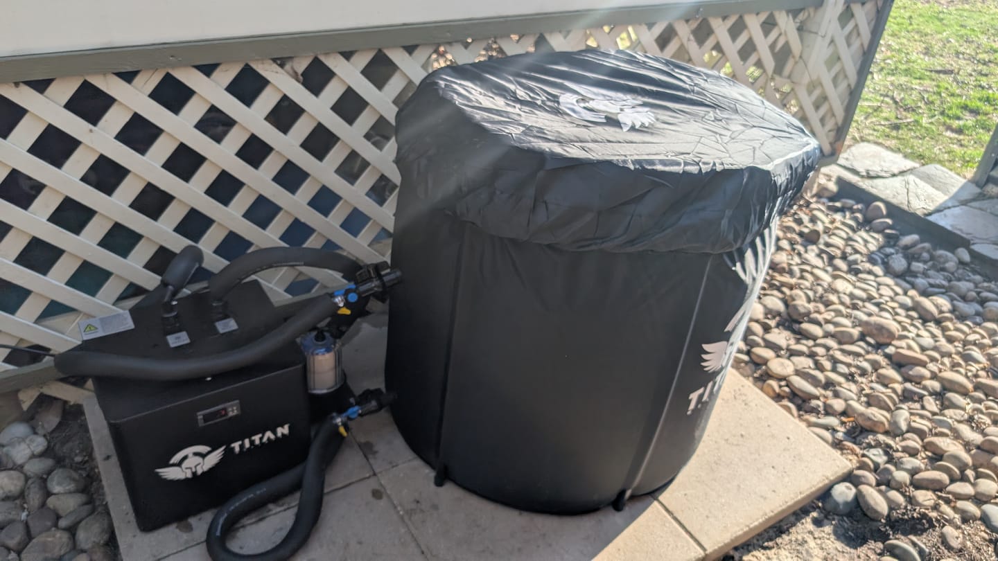 Customer review photo of Titan Bravo cold plunge with protective cover and Titan chiller, insulated hoses and 20 micron filter, outdoor patio by lattice fence and river rocks