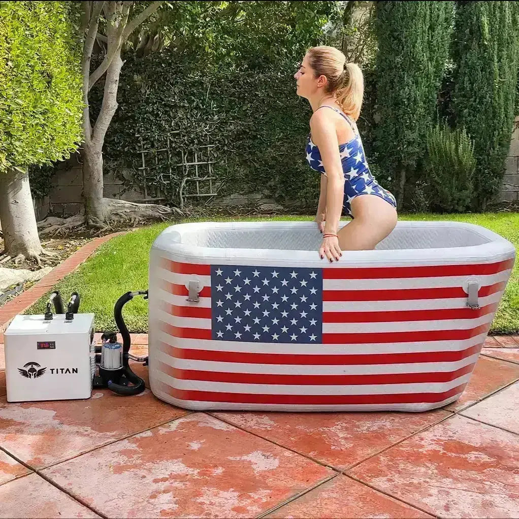 Inflatable cold tub with American flag design on a patio, woman in swimsuit standing inside.