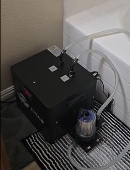 Customer review photo of Titan cold plunge chiller in bathroom beside bathtub, clear hoses connected and inline filter on bath mat